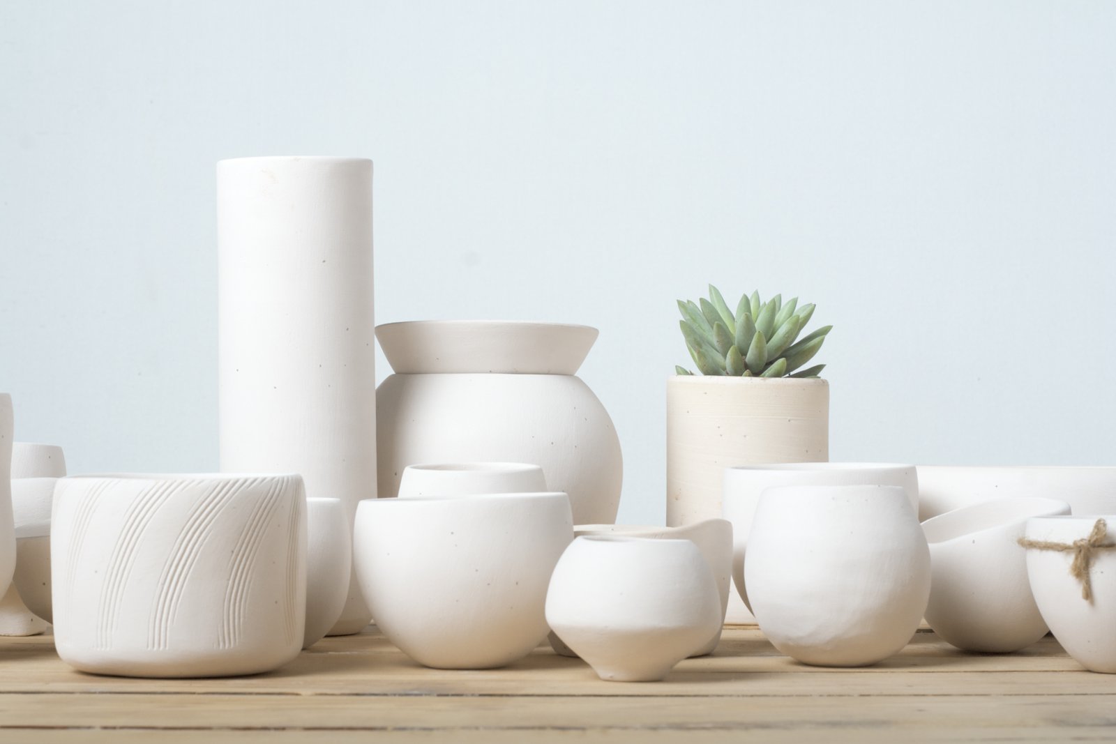 Unglazed white clay pots on wood table